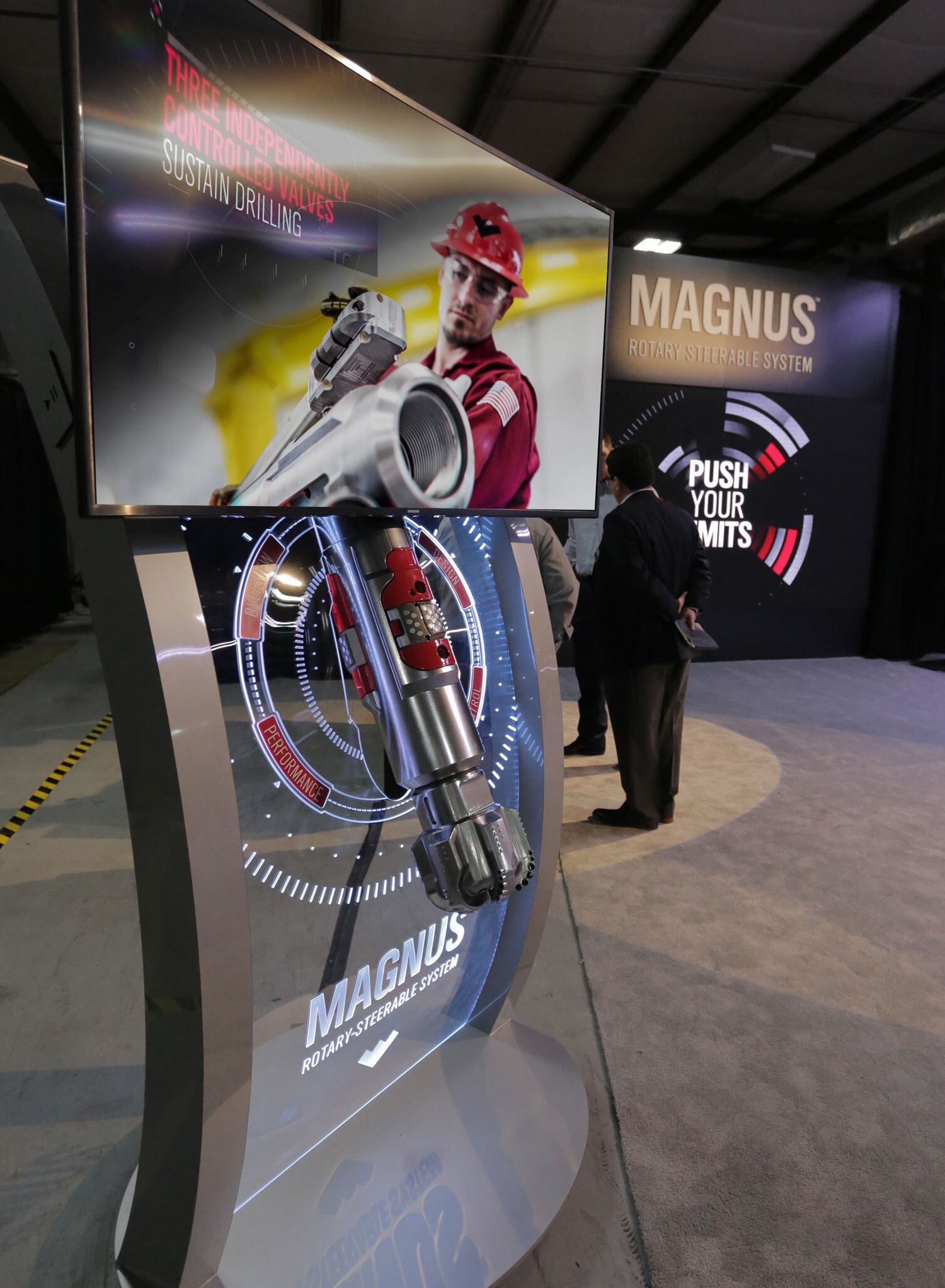 Magnus exhibit: a scale model of a downhole tool set in LED-lit etched acrylic, with a large screen above